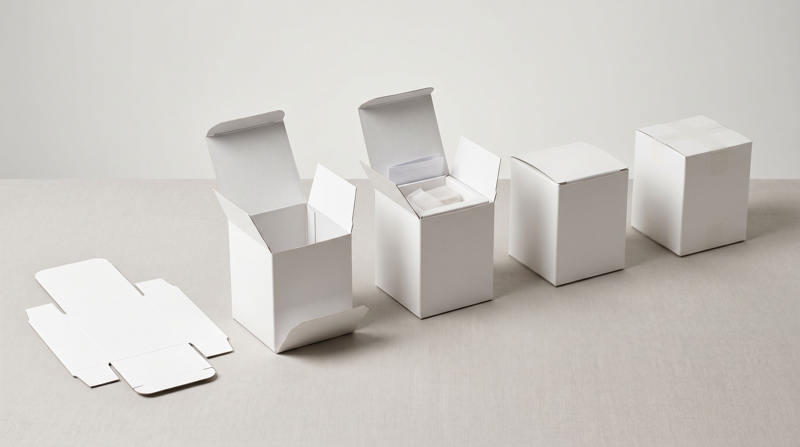 Five identical white product boxes arranged in a progressive processing sequence from empty to fully prepared.