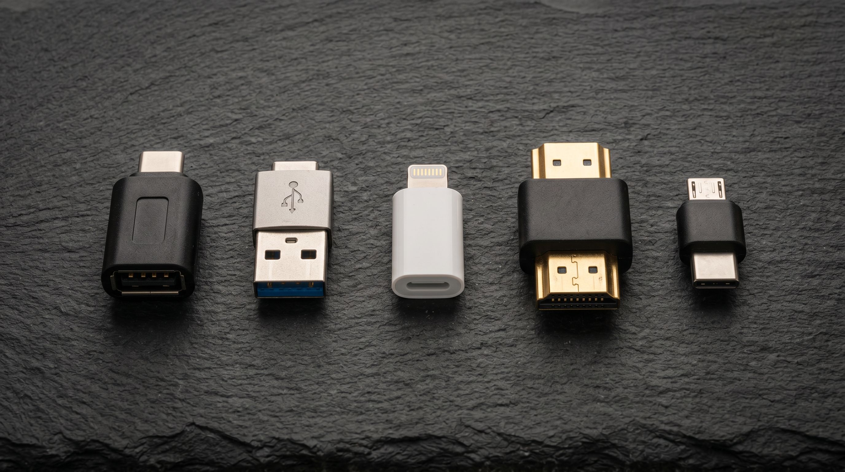 Five electronic connector adapters arranged in a row: USB-C, USB-A, Lightning, HDMI, and micro-USB connectors.