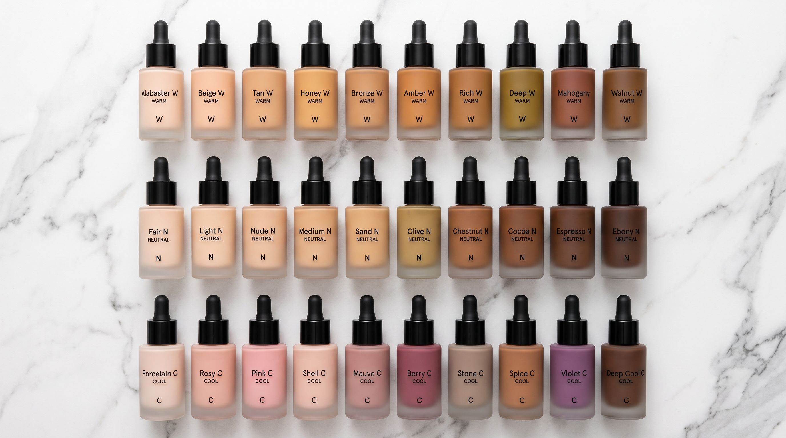 Three rows of foundation makeup bottles arranged by undertone on a white marble surface, viewed from directly above under even studio lighting.