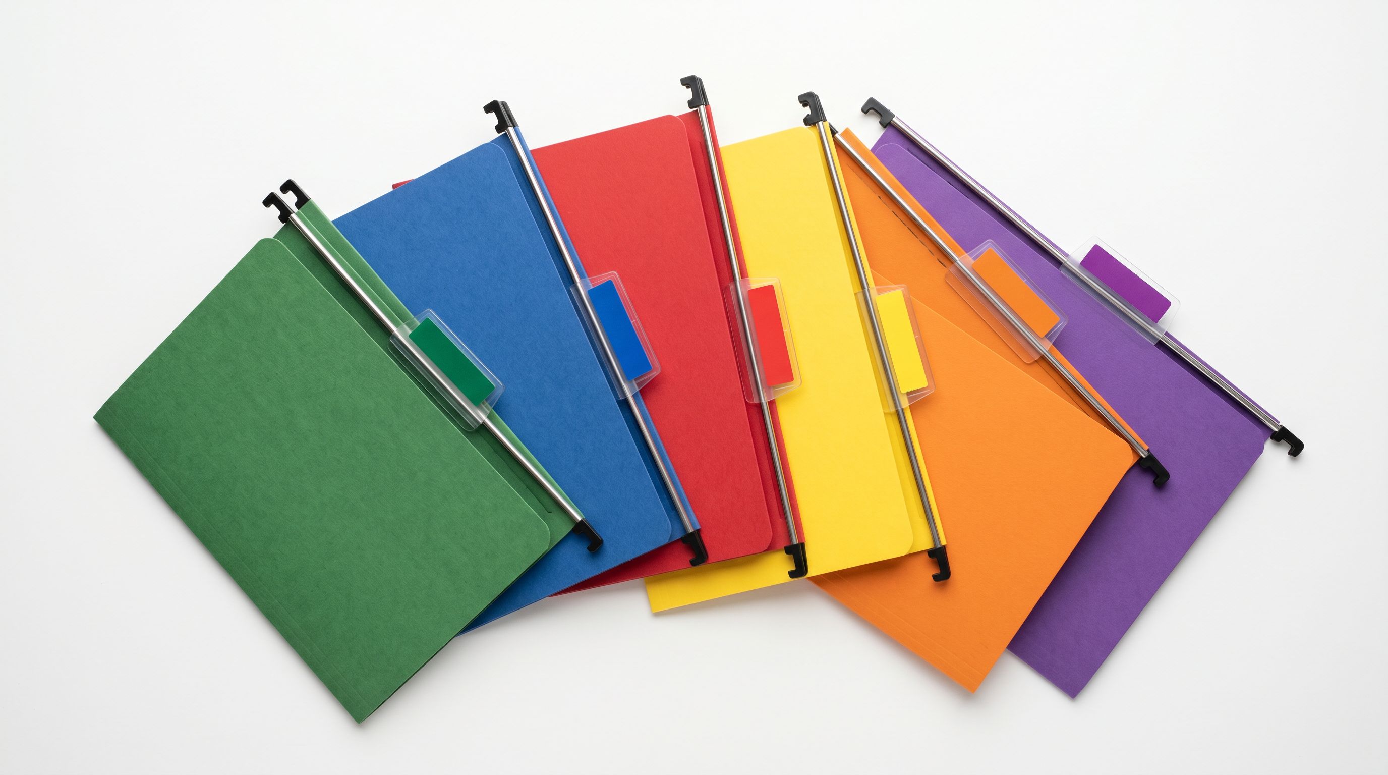Six suspension file folders with differently coloured label tabs fanned out on a clean white surface.