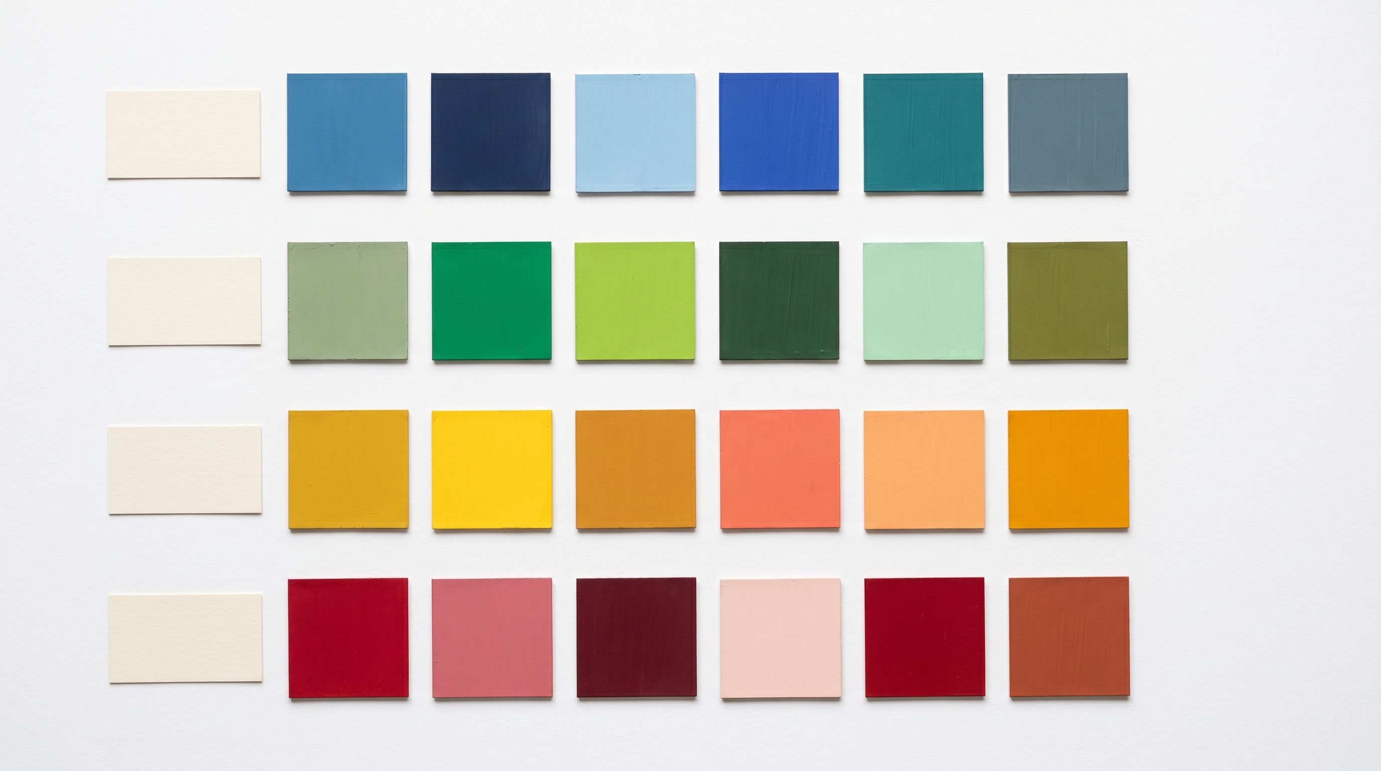 Paint colour swatches grouped by colour family in a grid arrangement on a white surface, with blank label cards beside each group.