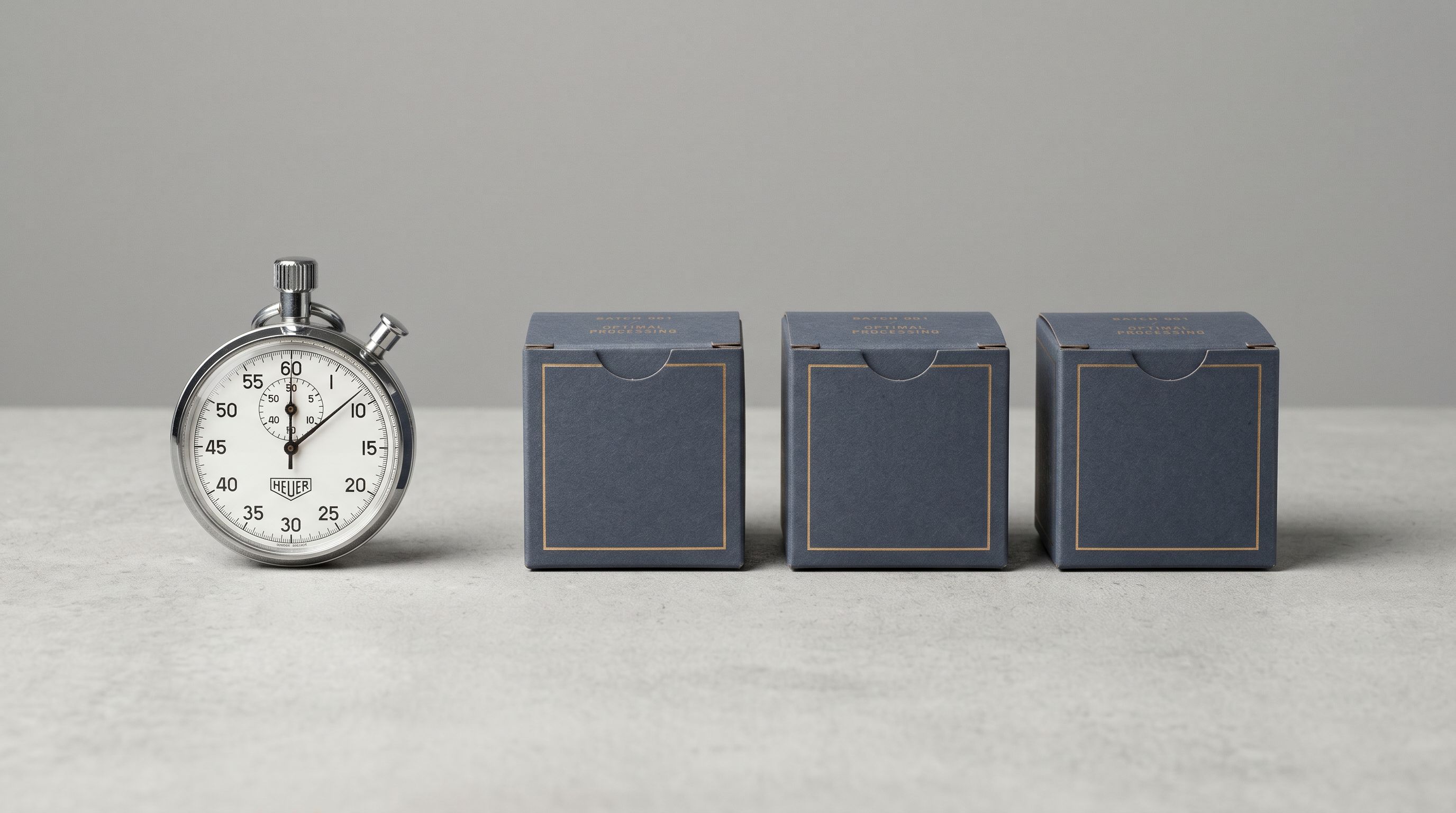 Stopwatch beside a row of identical product boxes on a clean surface representing timed batch processing.