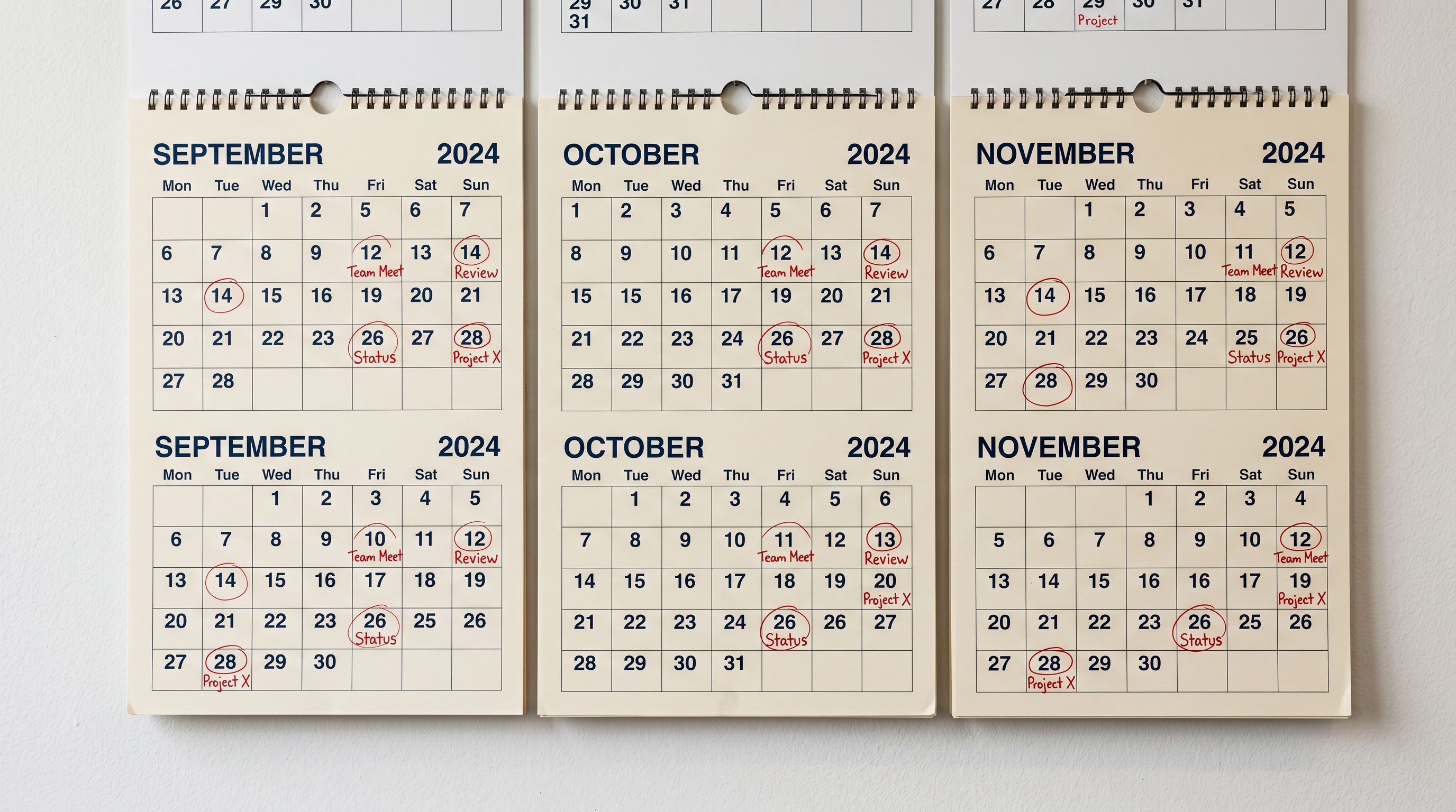 Wall-mounted calendar showing monthly scheduling marks with recurring event flags on a clean office wall.