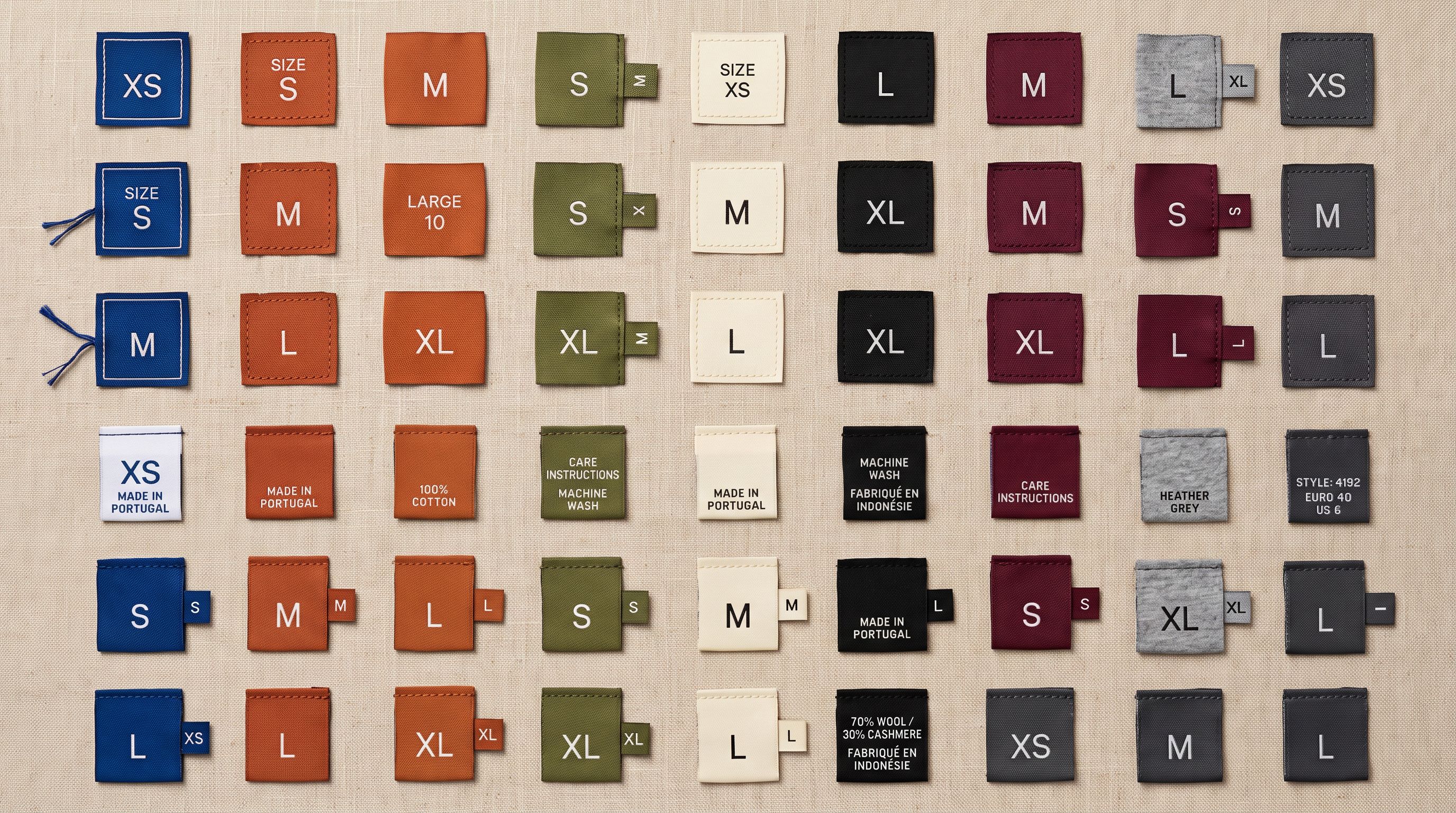 Close-up of product labels and size tags in multiple colour variants arranged in a systematic grid on a light surface showing organised variant classification